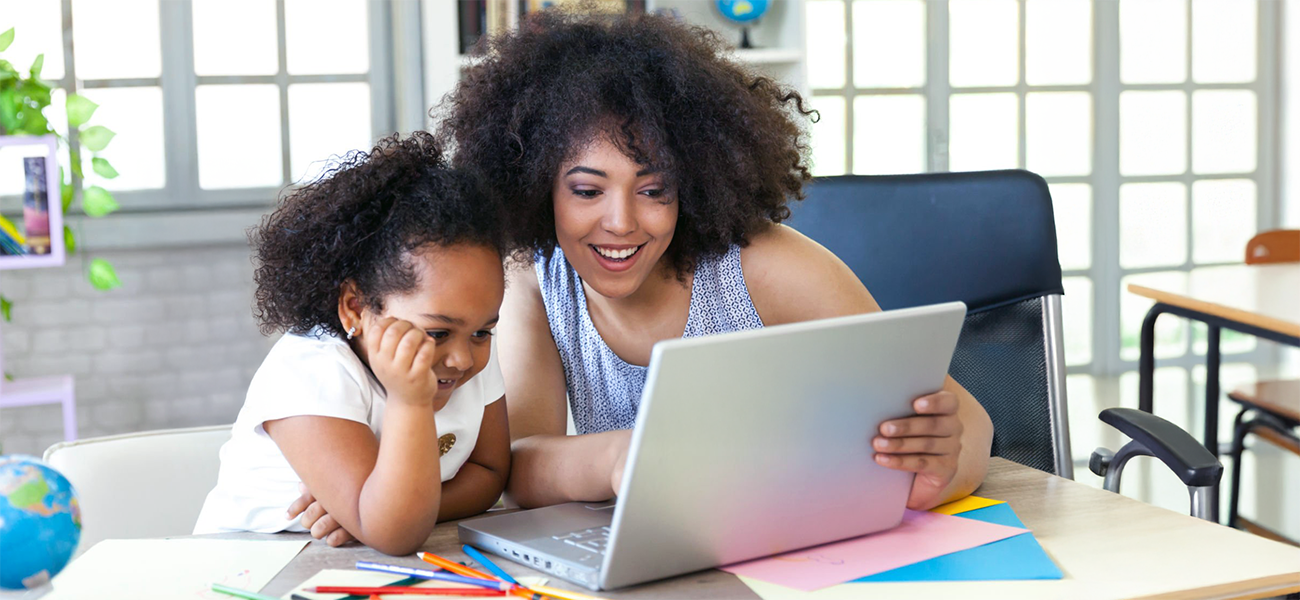 Image: Teacher helping a student with laptop.