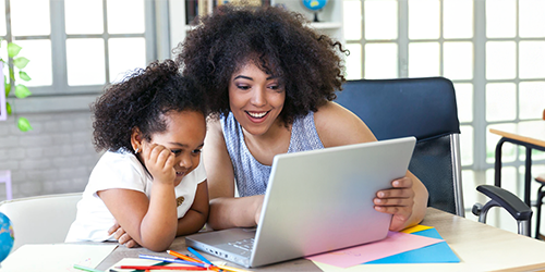 Image: Teacher helping a student with laptop.