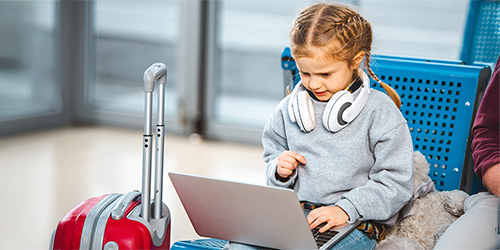 Image: Student using a laptop at a busy airport.