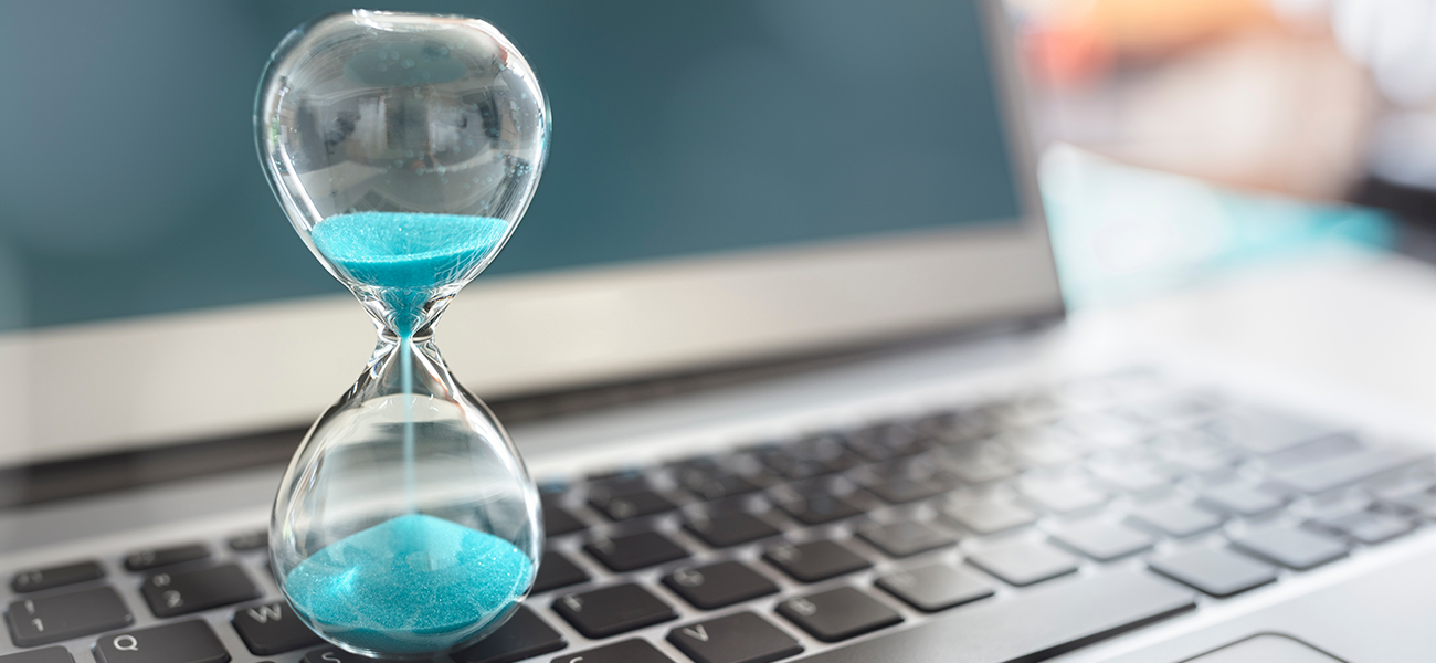 Picture of an hour glass with blue sand on a laptop.