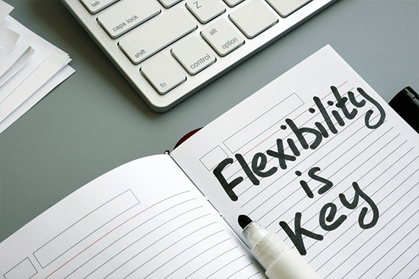 An open notebook that says 'Flexibility is Key' next to a keyboard.